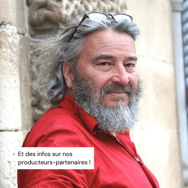 Producteur d'huile d'olive souriant barbu sur fond de bâtiment en pierre