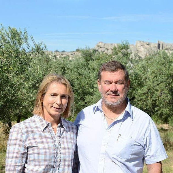 Couple de producteurs d'huile d'olive avec fond naturel de champ d'oliviers